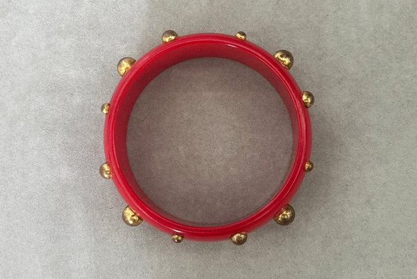 Horizontal top view of 1940s vintage brass studded rich cherry red Bakelite statement bangle bracelet.