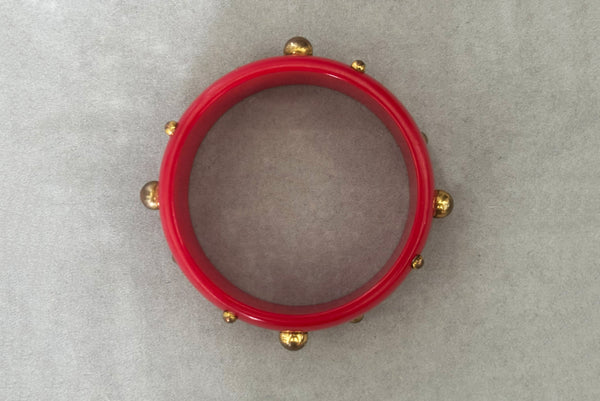 Horizontal bottom view of 1940s vintage brass studded rich cherry red Bakelite statement bangle bracelet.