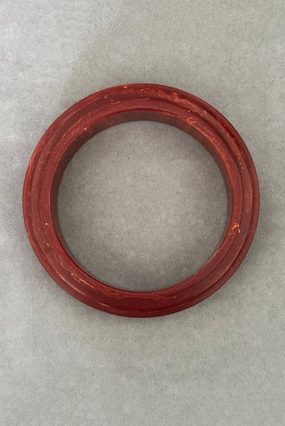 Vertical top view of 1940s vintage groove carved rust and yellow marbled Bakelite bangle bracelet.