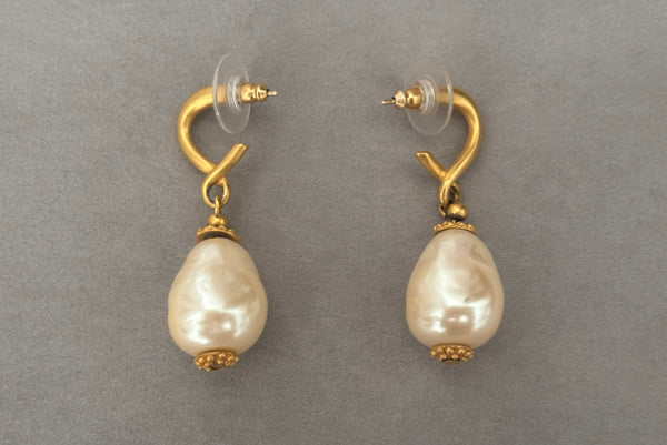 Horizontal side view of 1990s vintage gold tone matte metal and cream faux pearl pierced drop earrings.
