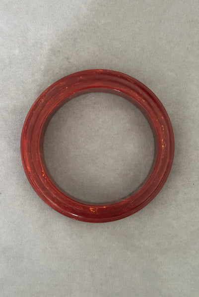 Vertical bottom view of 1940s vintage groove carved rust and yellow marbled Bakelite bangle bracelet.