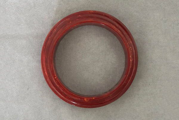 Horizontal bottom view of 1940s vintage groove carved rust and yellow marbled Bakelite bangle bracelet.