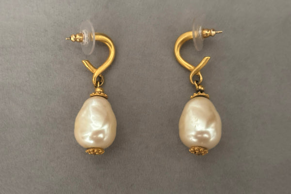 Horizontal side view of 1990s vintage gold tone matte metal and cream faux pearl pierced drop earrings.