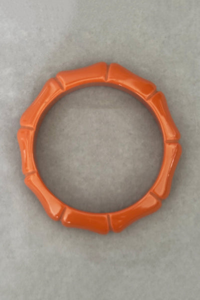 Vertical top view of 2000s y2k vintage orange plastic molded faux bamboo bangle bracelet.