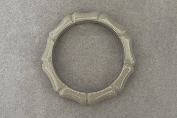 Horizontal top view of 2000s y2k vintage gray plastic molded faux bamboo bangle bracelet.