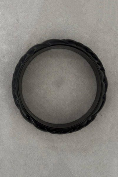 Vertical top view of 1980s vintage black plastic molded bangle bracelet.