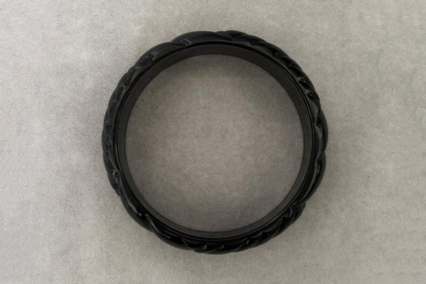 Horizontal top view of 1980s vintage black plastic molded bangle bracelet.