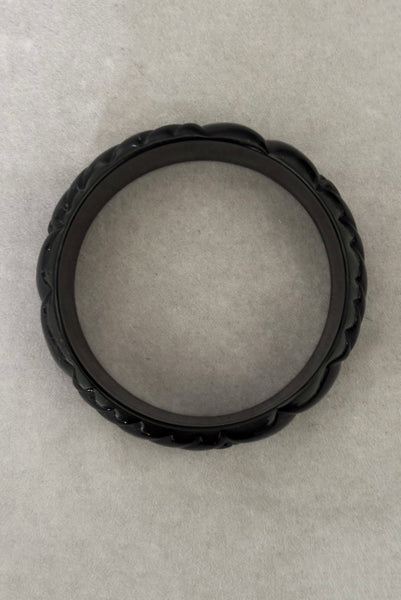 Vertical bottom view of 1980s vintage black plastic molded bangle bracelet.