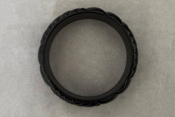 Horizontal bottom view of 1980s vintage black plastic molded bangle bracelet.