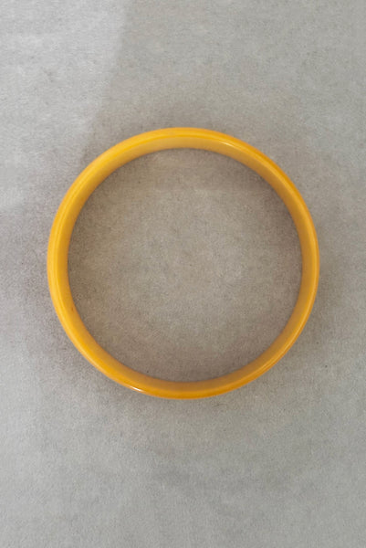 Vertical top view of 1940s vintage egg yolk yellow and mustard marbled Bakelite domed bangle bracelet