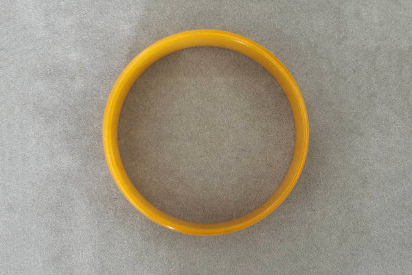 Horizontal top view of 1940s vintage egg yolk yellow and mustard marbled Bakelite domed bangle bracelet