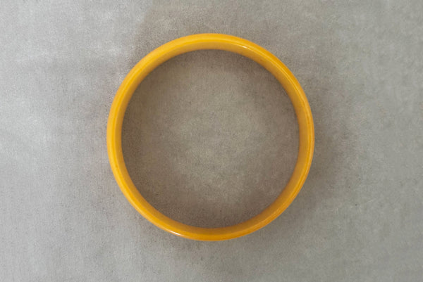 Horizontal bottom view of 1940s vintage egg yolk yellow and mustard marbled Bakelite domed bangle bracelet