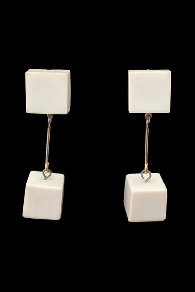 Vertical front view of 1960s vintage Mod gold tone and white Lucite cube bead top and drop clip-on dangle earrings.