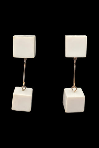 Vertical front view of 1960s vintage Mod gold tone and white Lucite cube bead top and drop clip-on dangle earrings.