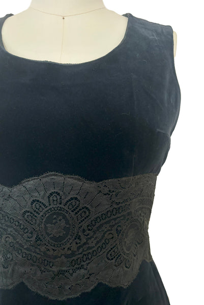 May include: A sleeveless black velvet dress with a black lace trim around the waist.