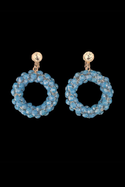 Vertical front view of 1950s vintage rhinestone, silver tone, and blue plastic beaded hoop clip-on statement earrings.