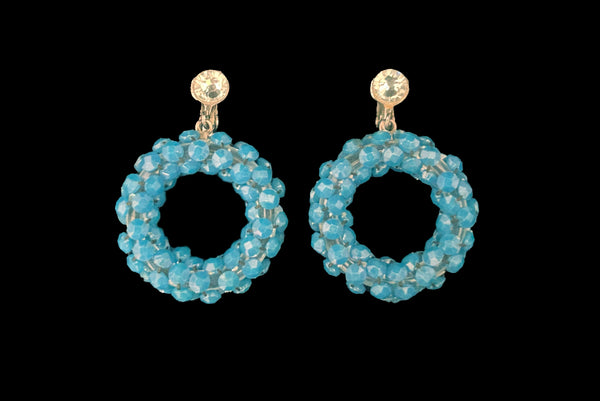 Horizontal front view of 1950s vintage rhinestone, silver tone, and blue plastic beaded hoop clip-on statement earrings.