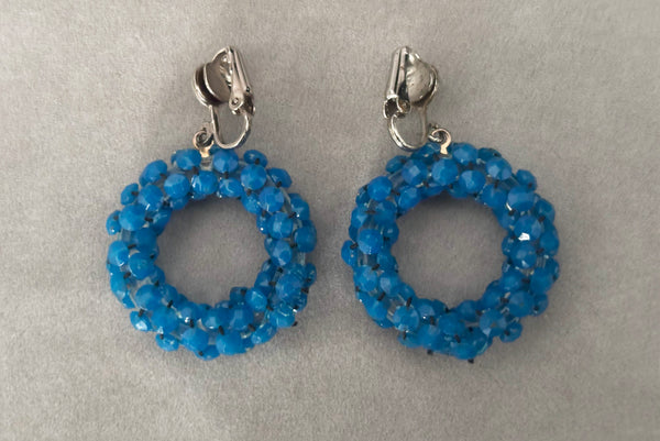 Horizontal back view of 1950s vintage rhinestone, silver tone, and blue plastic beaded hoop clip-on statement earrings.