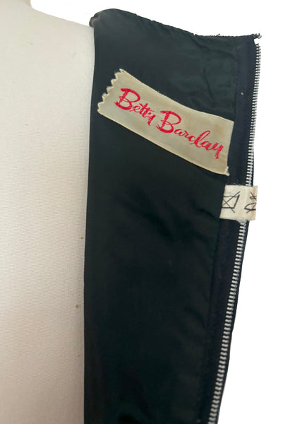 Interior detail view of 1950s vintage black velveteen dress with scalloped lace midriff by Betty Barclay, medium to large. Showing the Betty Barclay tag.