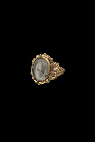 Vertical perspective view of 1990s vintage Victorian style floral brass ring with bezel set oval gray glass cabochon, size 8.