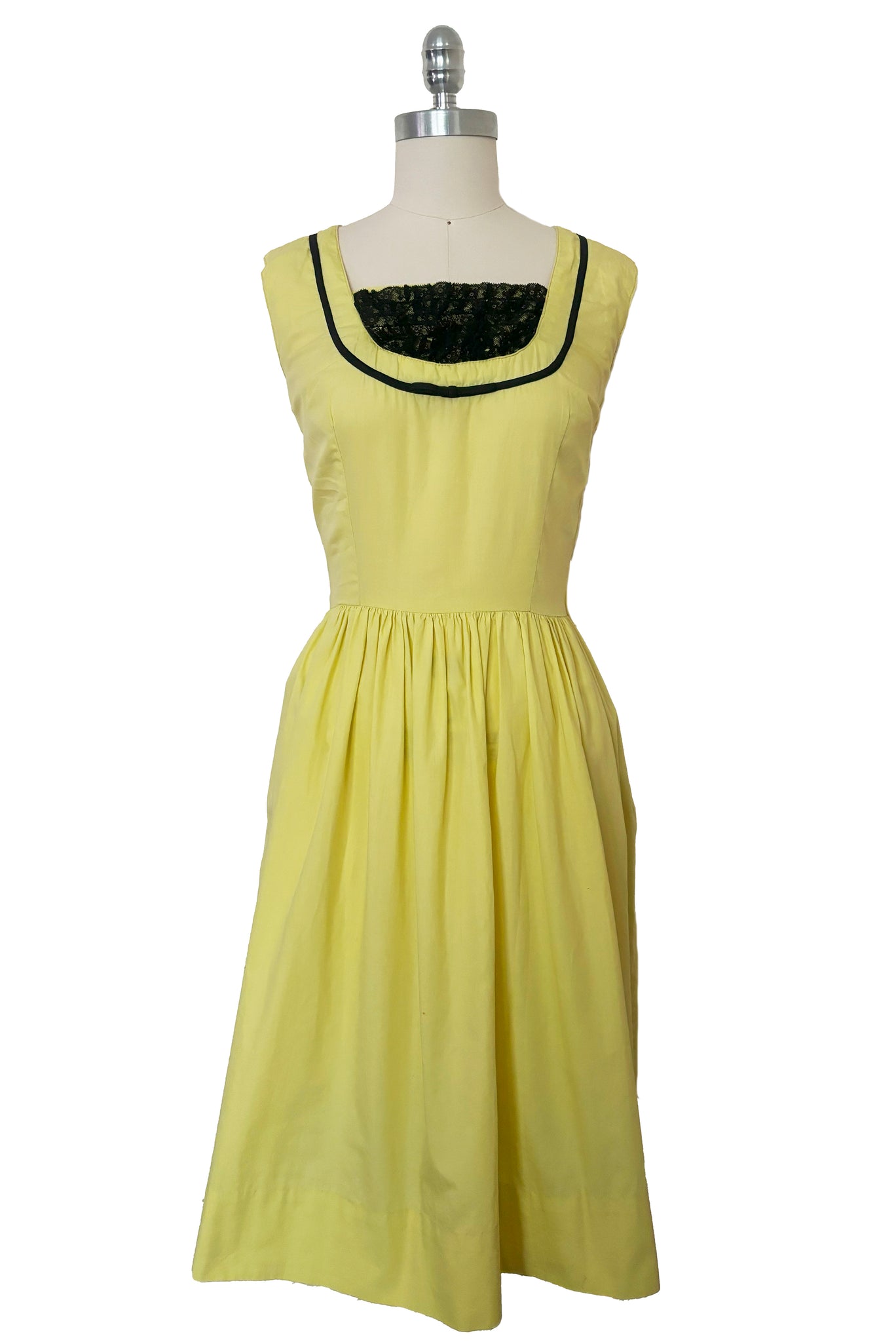 Front view of 1950s vintage chartreuse yellow/green cotton black ruffle inset neckline and trim sleeveless sundress with gathered skirt, size small to medium.