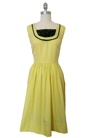 Front view of 1950s vintage chartreuse yellow/green cotton black ruffle inset neckline and trim sleeveless sundress with gathered skirt, size small to medium.