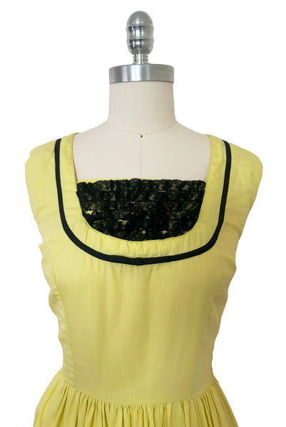 Bodice front view of 1950s vintage chartreuse yellow/green cotton black ruffle inset neckline and trim sleeveless sundress with gathered skirt, size small to medium.