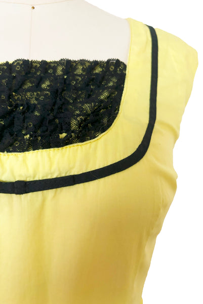 Bodice front view of 1950s vintage chartreuse yellow/green cotton black ruffle inset neckline and trim sleeveless sundress with gathered skirt, size small to medium.