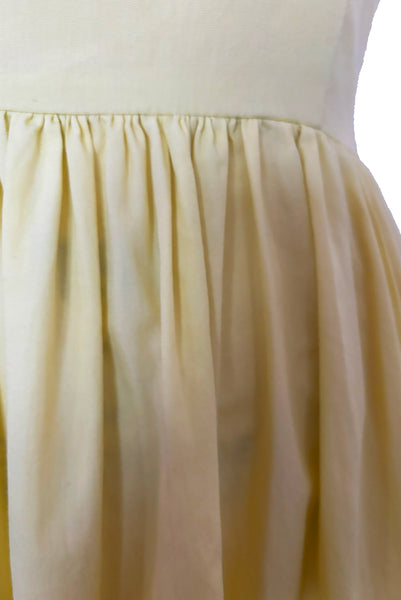 Bodice front view of 1950s vintage chartreuse yellow/green cotton black ruffle inset neckline and trim sleeveless sundress with gathered skirt, size small to medium. Showing a light spot on the skirt.