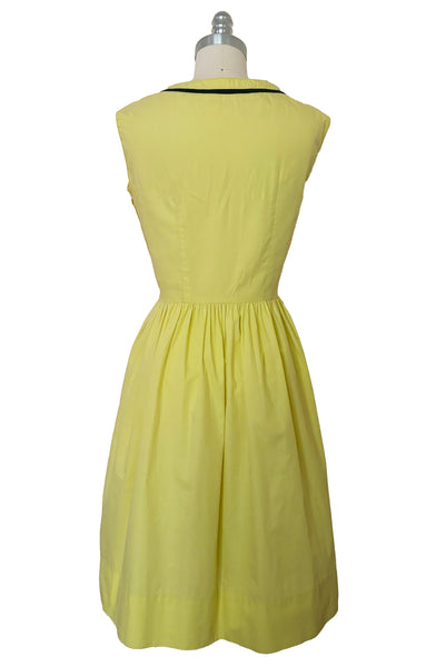 Front view of 1950s vintage chartreuse yellow/green cotton black ruffle inset neckline and trim sleeveless sundress with gathered skirt, size small to medium.
