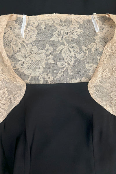 Detail view of 1930s vintage cream lace sheer back Juliet sleeve square neck black crepe midi dress, size extra small to small. Showing a flat view of the square neckline and two small darts taken in the neckline of the sheer back to repair some damage.
