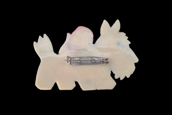 Horizontal back view of 1950s vintage cream celluloid plastic red and pale blue painted Scottie dog brooch with rhinestone eye.