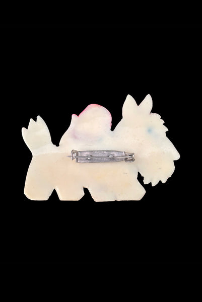 Vertical back view of 1950s vintage cream celluloid plastic red and pale blue painted Scottie dog brooch with rhinestone eye.