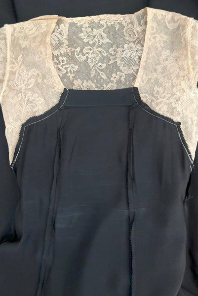 Detail view of 1930s vintage cream lace sheer back Juliet sleeve square neck black crepe midi dress, size extra small to small. Showing a flat view of the interior bodice front showing a little interior discoloration.