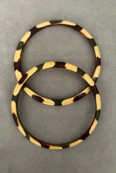 Vertical top view of 1960s vintage cream, purple, and green celluloid two (2) bangle bracelet set. Showing the pair of bangles together.