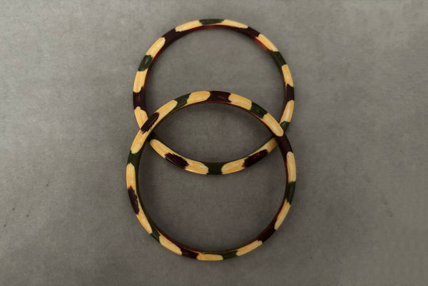 Horizontal top view of 1960s vintage cream, purple, and green celluloid two (2) bangle bracelet set. Showing the pair of bangles together.