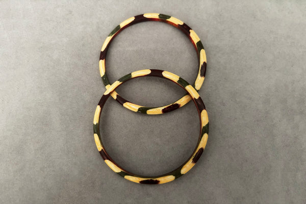 Horizontal top view of 1960s vintage cream, purple, and green celluloid two (2) bangle bracelet set. Showing the pair of bangles together.