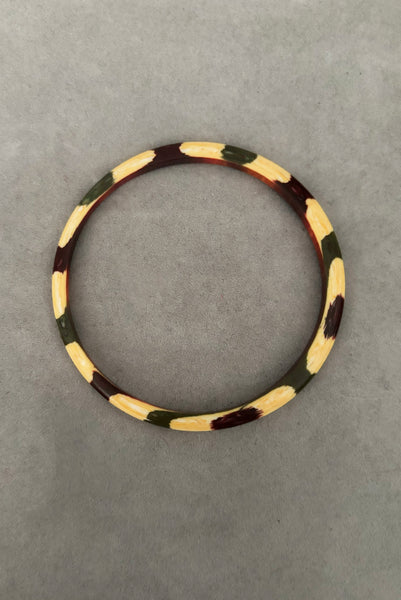 Vertical top view of 1960s vintage cream, purple, and green celluloid two (2) bangle bracelet set. Showing a single bangle.