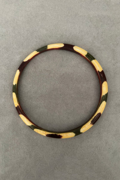 Vertical top view of 1960s vintage cream, purple, and green celluloid two (2) bangle bracelet set. Showing a single bangle.