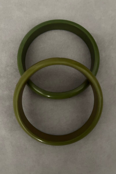 Vertical top view of 1980s vintage green plastic two (2) bangle bracelet set inlaid with gold tone brass dots. Showing the two bangles together.
