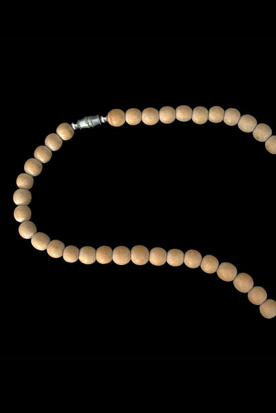 Detail view of 1980s vintage carved round and disk bead light, medium, and dark triple tone wood necklace. Showing a close-up of the silver tone barrel clasp.