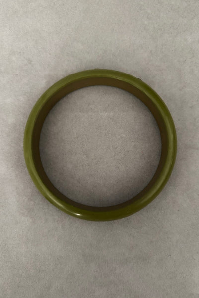 Vertical top view of 1980s vintage green plastic two (2) bangle bracelet set inlaid with gold tone brass dots. Showing the lighter bangle.