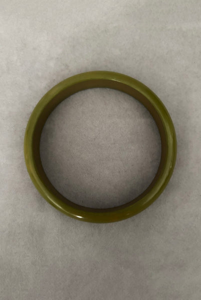 Vertical bottom view of 1980s vintage green plastic two (2) bangle bracelet set inlaid with gold tone brass dots. Showing the lighter bangle.