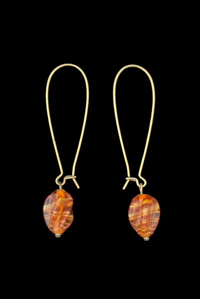 Vertical side view of 2010s vintage marbled orange glass lampwork beads on long gold tone earwire drop earrings.