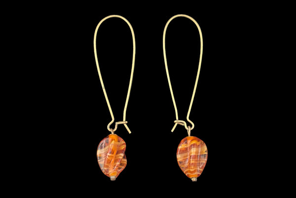 Horizontal side view of 2010s vintage marbled orange glass lampwork beads on long gold tone earwire drop earrings.