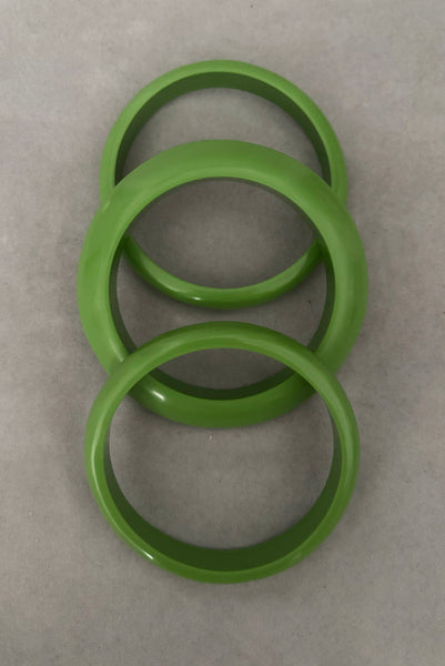 Vertical top view of 1980s vintage leaf green two (2) domed, and one (1) saucer three (3) bangle bracelet set. Showing the three bangles.