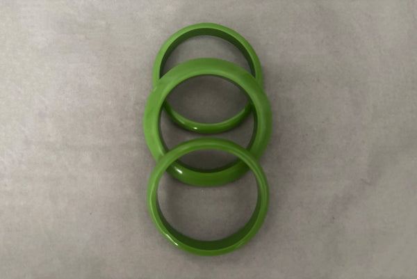 Horizontal top view of 1980s vintage leaf green two (2) domed, and one (1) saucer three (3) bangle bracelet set. Showing the three bangles.