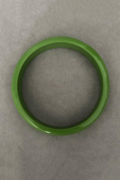 Vertical top view of 1980s vintage leaf green two (2) domed, and one (1) saucer three (3) bangle bracelet set. Showing one domed bangle.