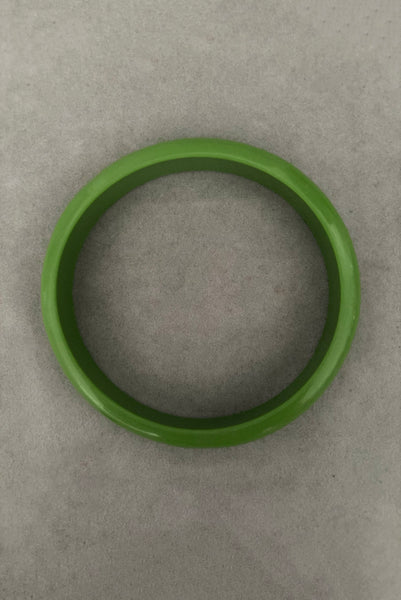 Vertical top view of 1980s vintage leaf green two (2) domed, and one (1) saucer three (3) bangle bracelet set. Showing one domed bangle.