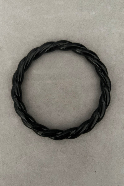 Vertical top view of 1980s vintage black plastic twisted, ridged, and orange goldfish painted bangle bracelet set of three (3). Showing the twisted rope bangle only.